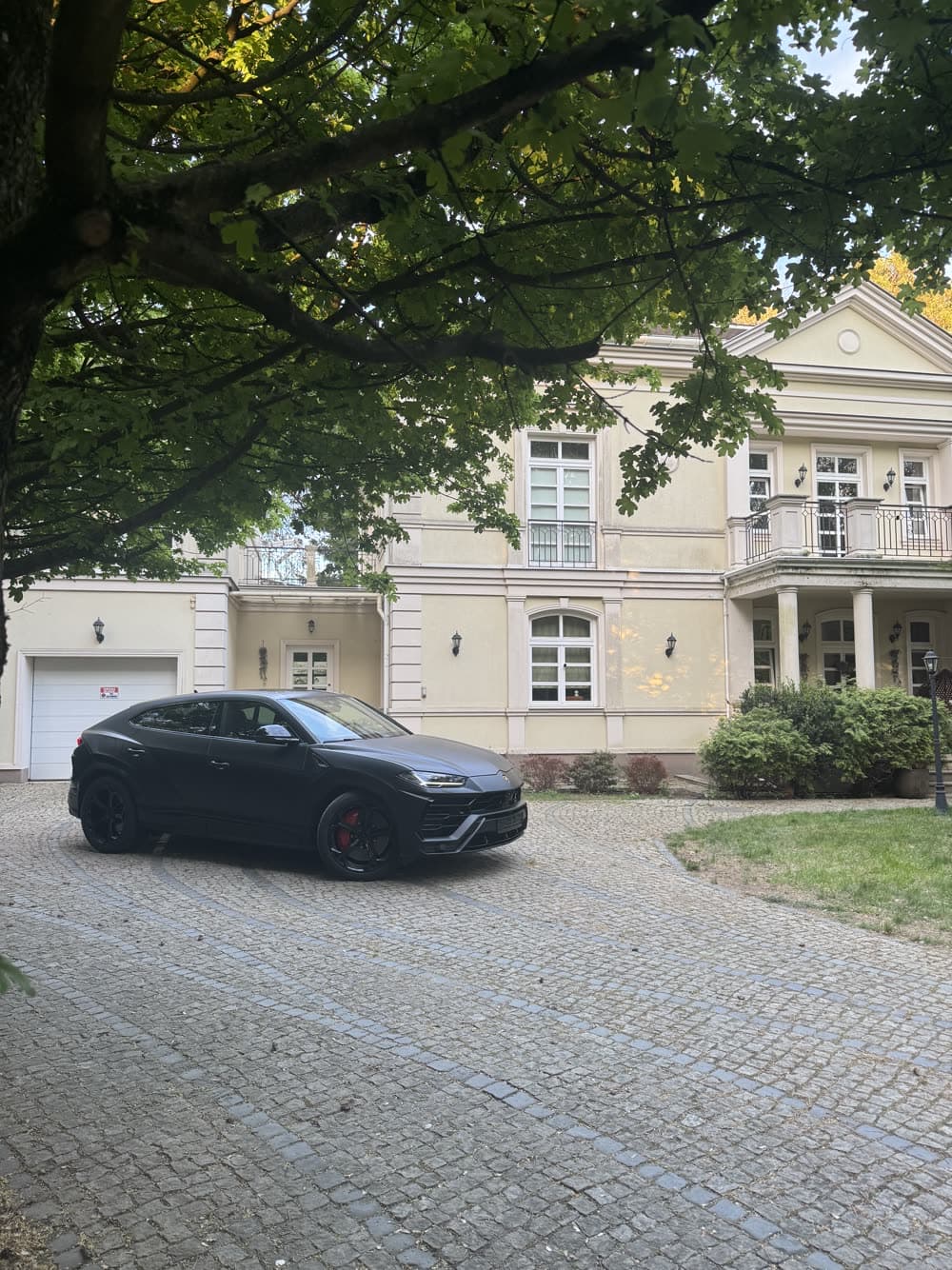 Czarne Lamborghini Urus zaparkowane na podjeździe przed domem